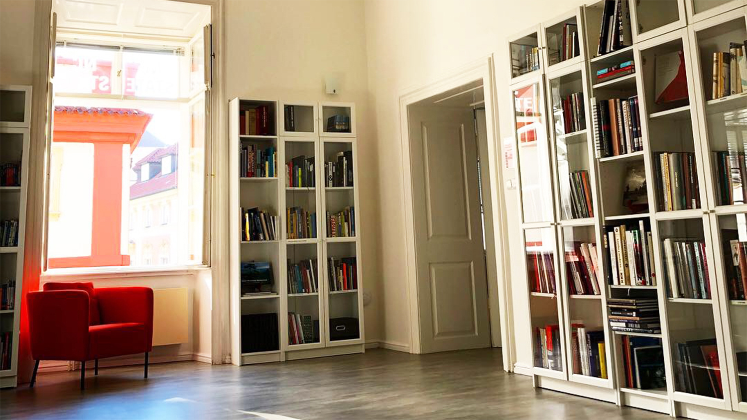 Library space with shelves with books and a red armchair.