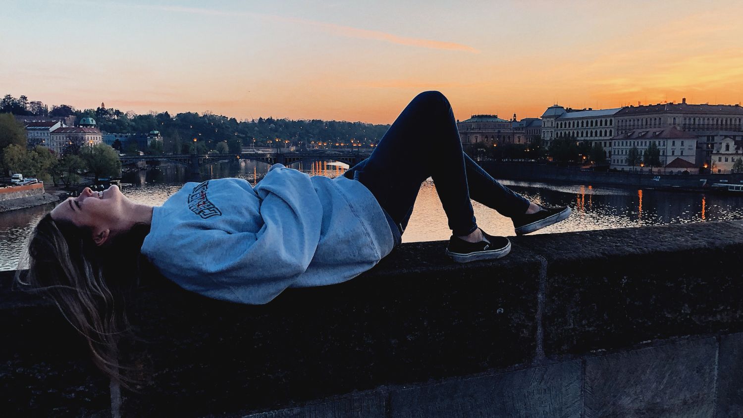 A student, Sydney, lying on the side of Charles Bridge at sunset