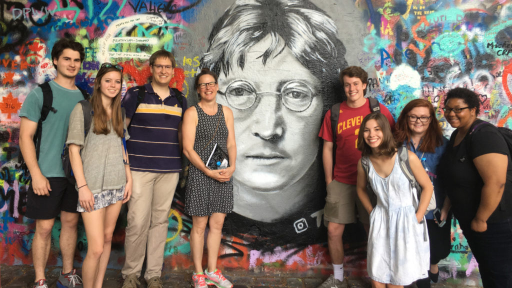 Teachers and students stand in front of the John Lennon wall in Prague.