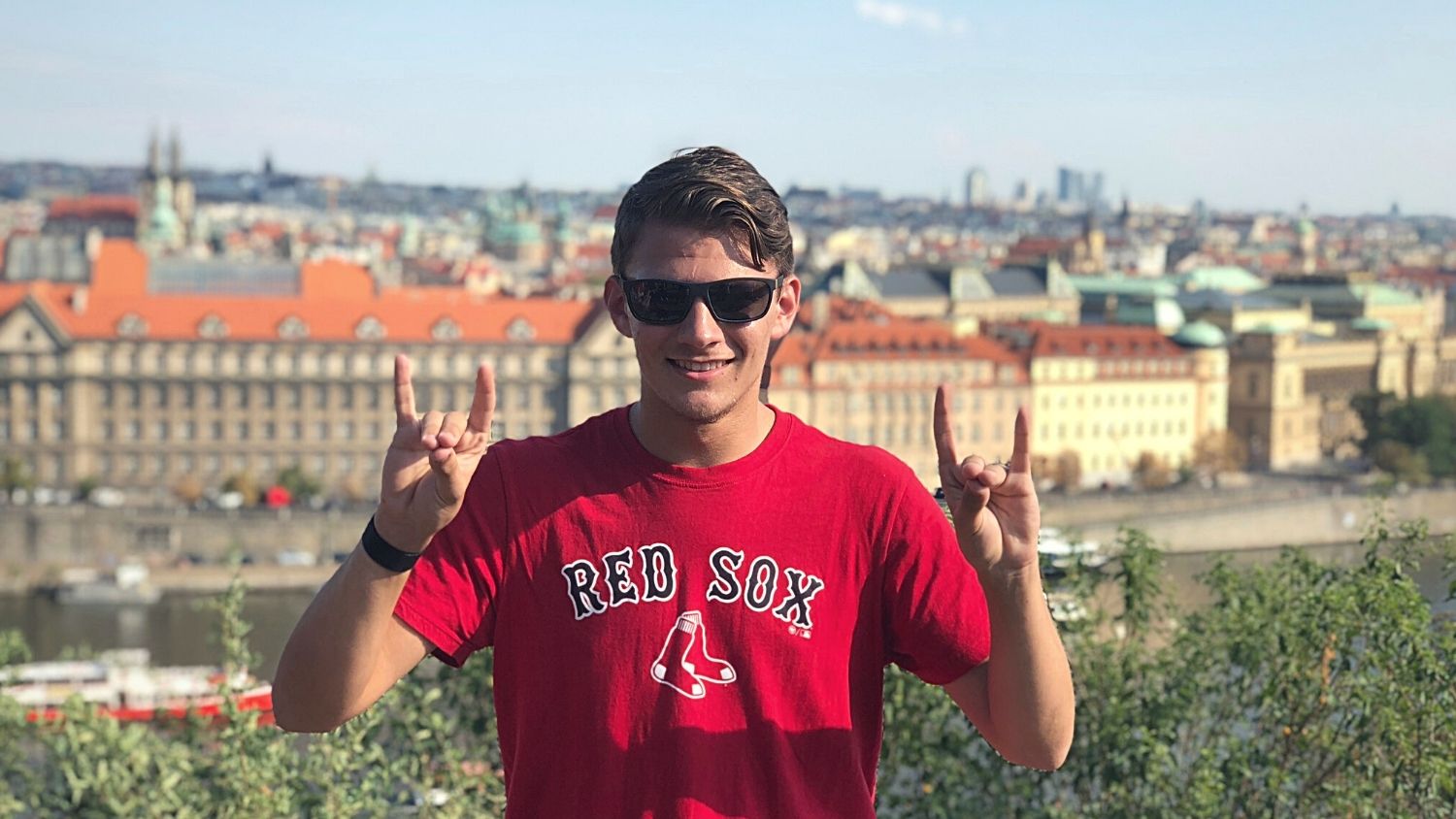 A student, Caleb, in a park with Prague's rooftops in the background