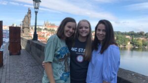A student, Shea, with two of her friends on the Charles Bridge with Prague Castle in the background.