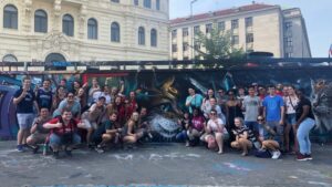 A group photo of students in front of a wall covered with graffiti