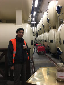 A student, Felix, taking a coffee break at a storage room with huge tankers surrounding him.