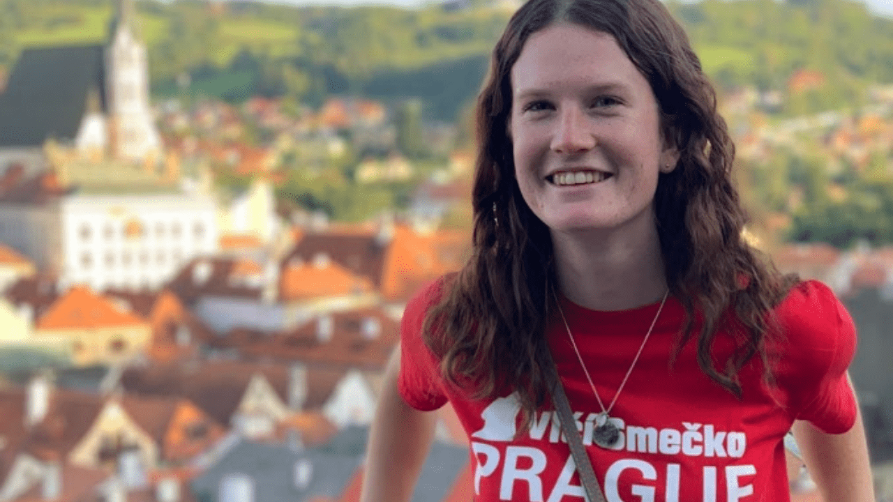 Close up on an NC State Prague student wearing the red tshirt of the Center with Cesky Krumlov in the background