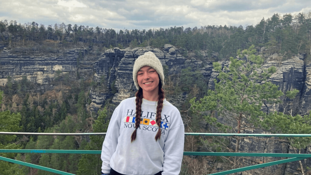 Student smiling in front of a rock formation in Czech Switzerland