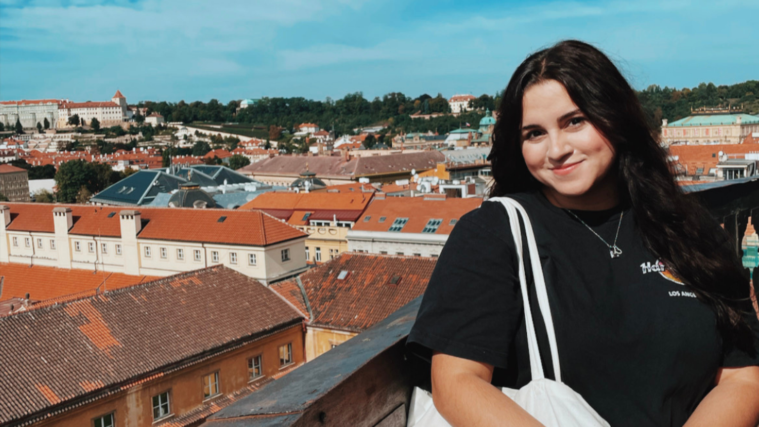 Elizabeth Vanegas taking a photo with the rooftops of Prague in the background