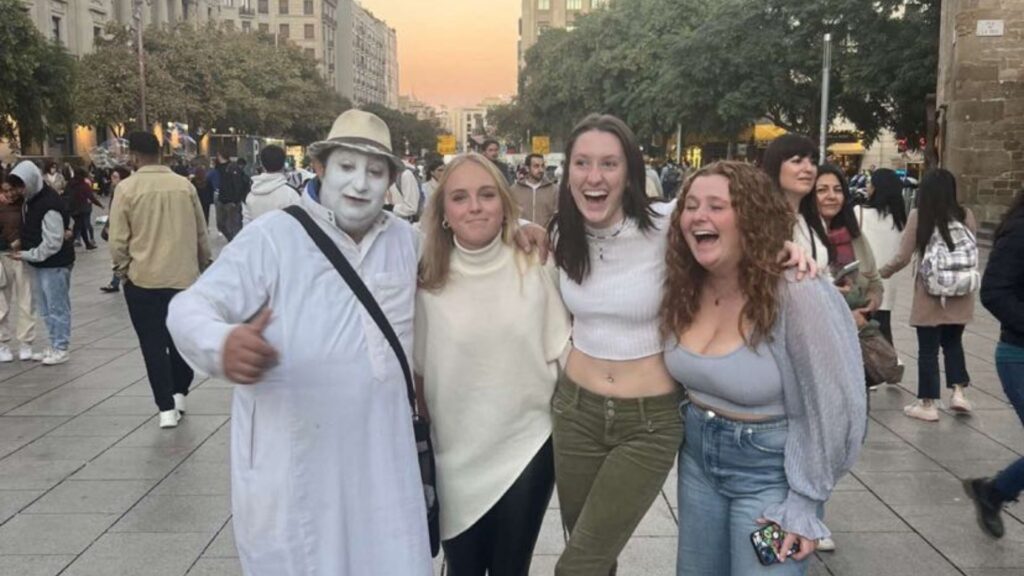 A student, Rowan, with two of her friends posing for a photo with a mime artist.