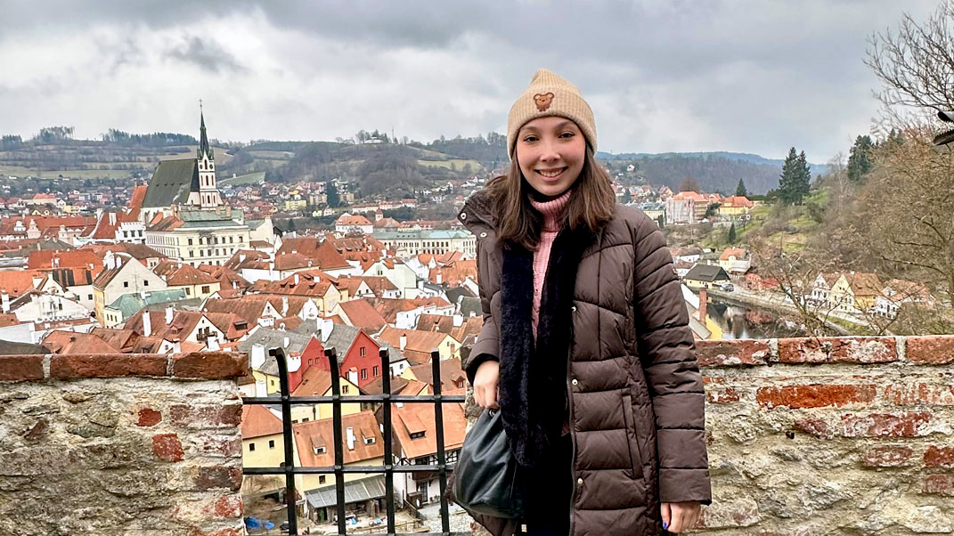 A photo of a student with Český Krumlov in the background