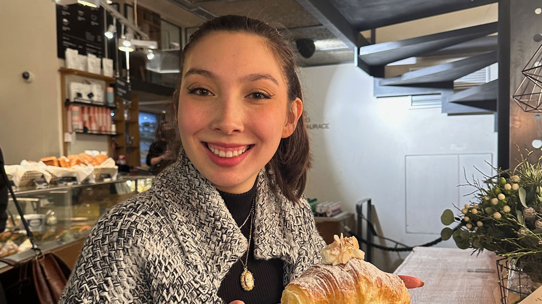 Student in a cafe holding sweet pastry