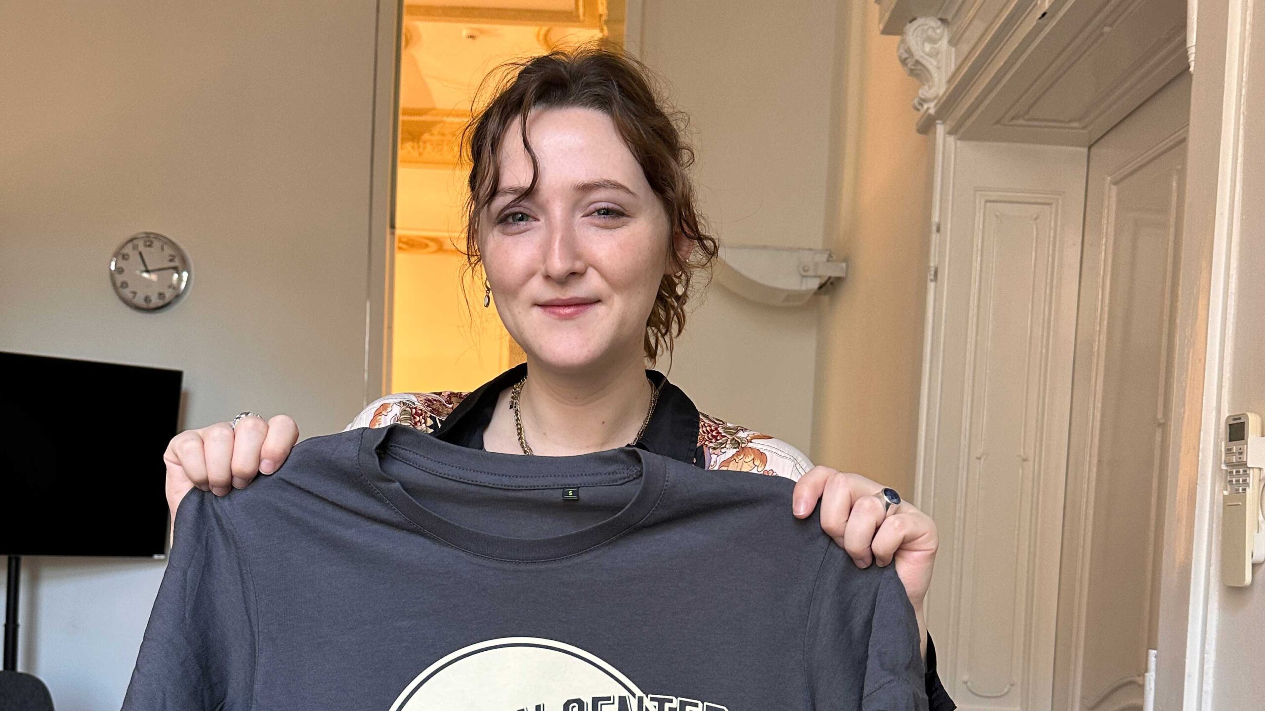 Sadie holding a newly arrived tshirt with the design of the Center which she had designed.