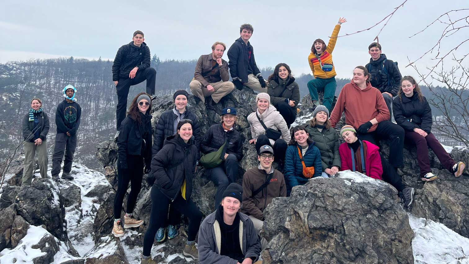 Group of students posing on rocks, surrounded by snow