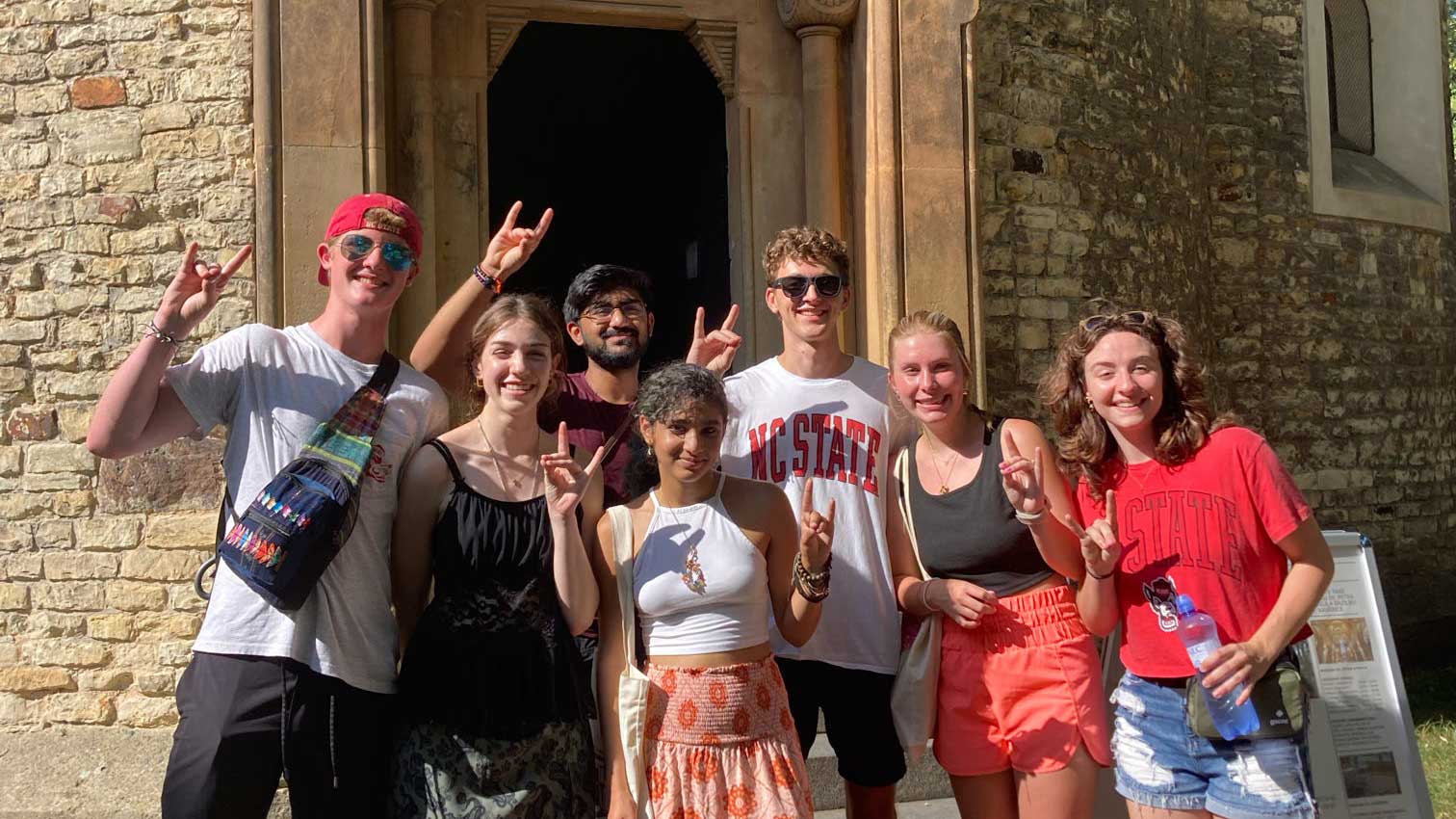 7 students posing in front of a chapel