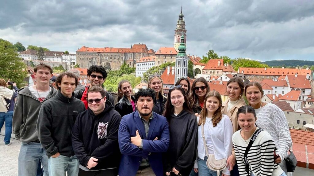 Group of students posing in front of the cityscape of Cesky Krumlov.