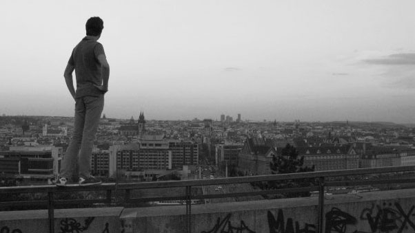 Black and white photograph of a student standing on a viewpoint overlooking the city of Prague