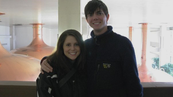 Couple standing next to each other posing for a picture in a brewery