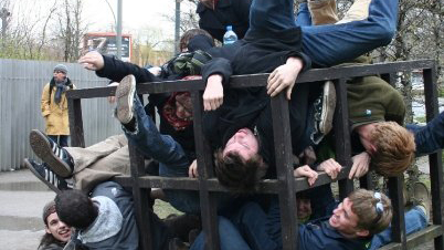 Bunch of students having fun, being all tangled up in a big metal cube